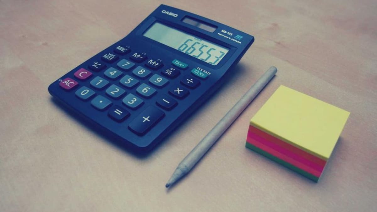 Masaüstünde hesap makinesi ve grafik kağıtlarıyla çalışan bir kişi