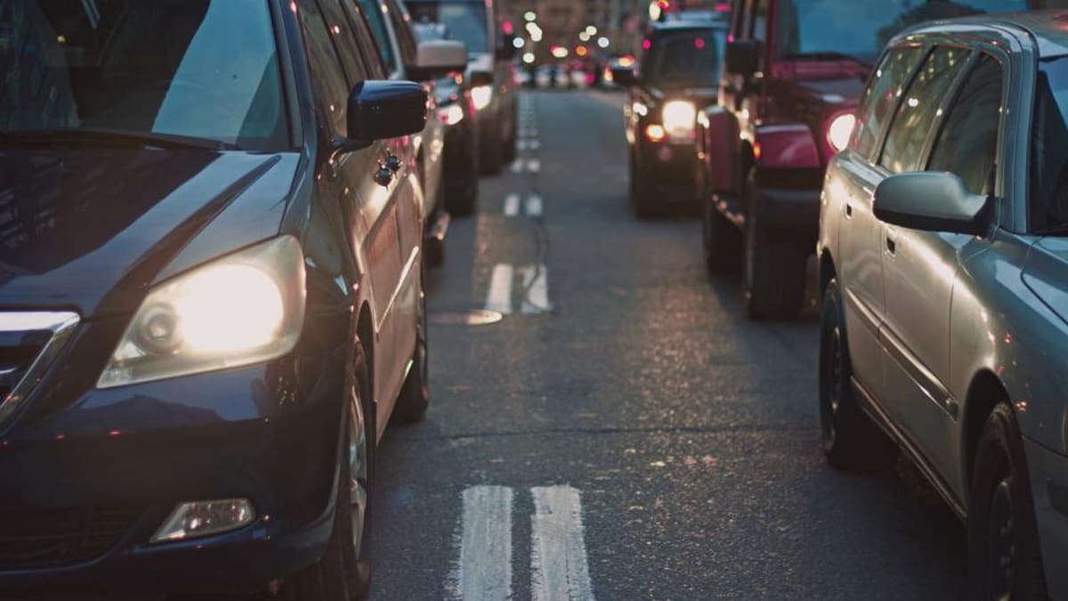 Akşam saatlerinde şehir içi bir yolda şeritlerde sıralanmış, farları yanan otomobiller