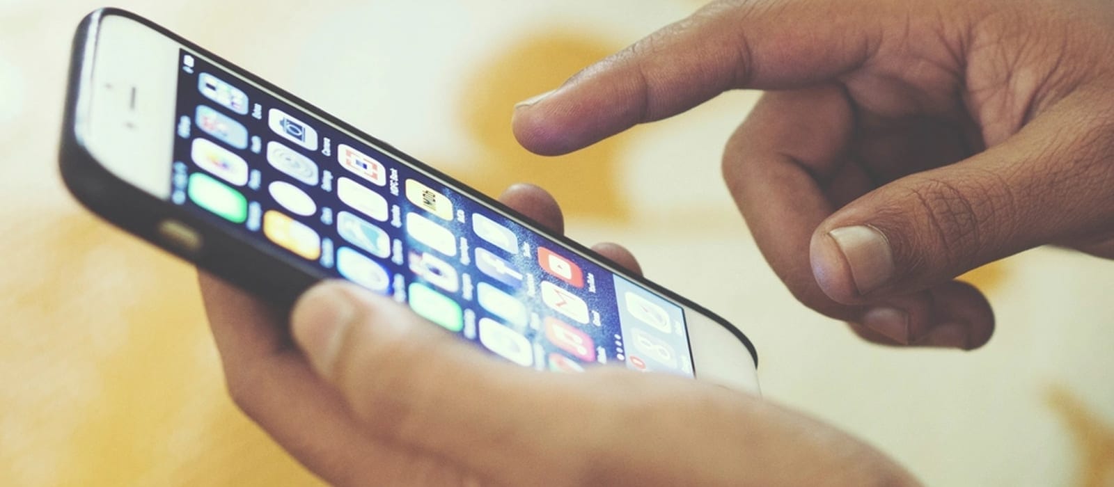 Bir kişinin elinde tuttuğu akıllı telefon ekranına dokunurken görünen yakın çekim
